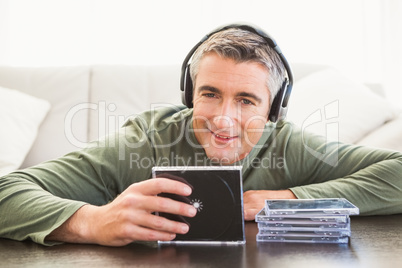 Smiling man listening music and holding cd