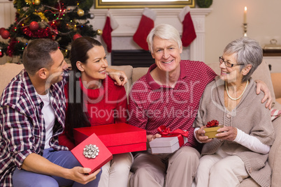 Smiling family holding gift on sofa