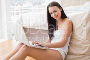 Pretty brunette using laptop sitting on floor