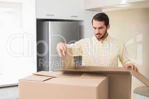 Young man unpacking boxes in kitchen