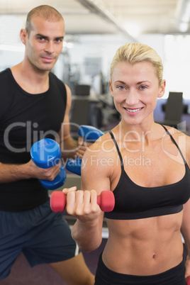 Couple exercising with dumbbells in gym