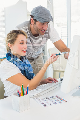Cheerful photo editor pointing at a computer