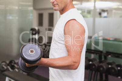 Fit man lifting heavy black dumbbell