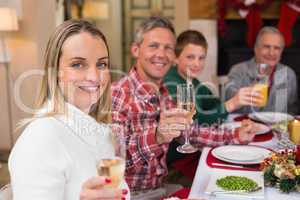 Smiling family toasting to camera during christmas dinner