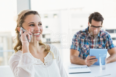 Blonde woman on the phone with her colleague behind Blonde woman on the phone with her colleague behind