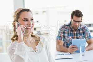 Blonde woman on the phone with her colleague behind