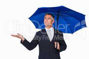 Smiling businessman under umbrella with hand out