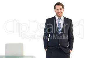 Smiling businessman standing with hands in pockets