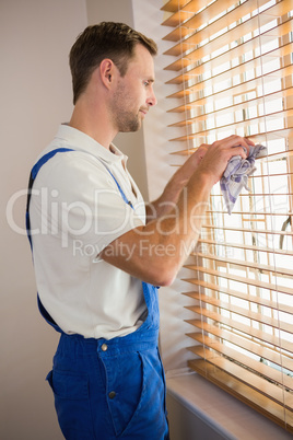 Manual worker cleaning blinds with a towel