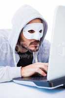 Man wearing mask while hacking into laptop