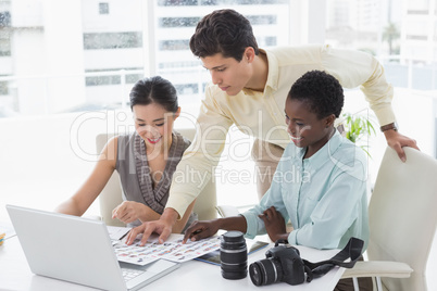 Casual business team looking at laptop together