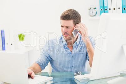 Businessman on the phone using his laptop at desk