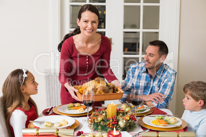 Smiling woman serving roast turkey to her family