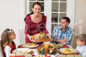 Smiling woman serving roast turkey to her family