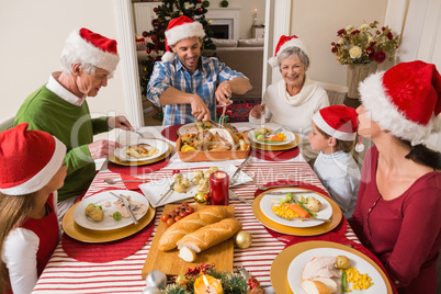 Father in santa hat carving roast turkey at christmas