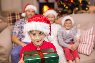 Smiling son holding gift in front of his family Smiling son holding gift in front of his family