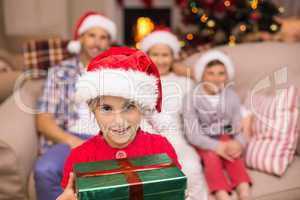 Smiling son holding gift in front of his family