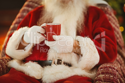 Mid section of santa holding hot drink