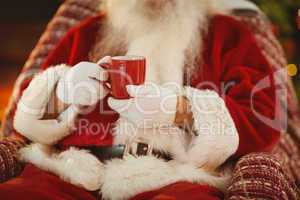 Mid section of santa holding hot drink
