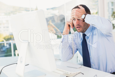 Shocked businessman on phone at his desk