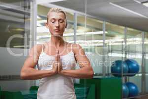 Woman with joined hands and eyes closed at fitness studio