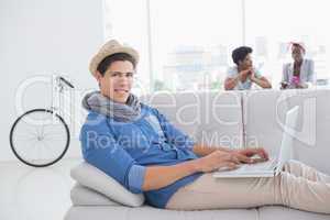 Young creative man using laptop on couch