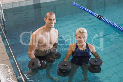 Swimmers working out with foam dumbbells in swimming pool at lei