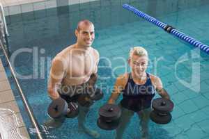 Swimmers working out with foam dumbbells in swimming pool at lei