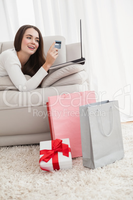 Pretty brunette shopping online on couch