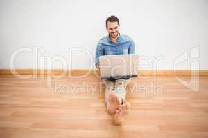 Casual man sitting on floor using laptop