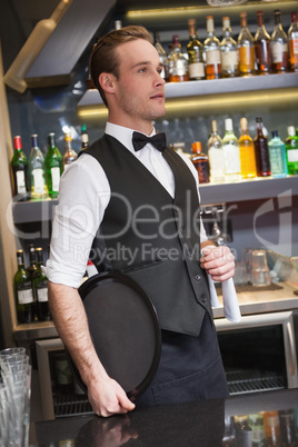 Serious waiter holding tray and towel