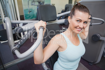 Fit brunette using weights machine for arms