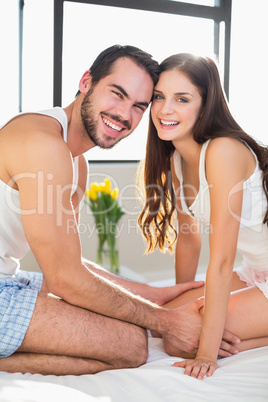 Young couple smiling at camera in bed