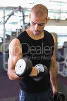 Young man exercising with dumbbell in gym