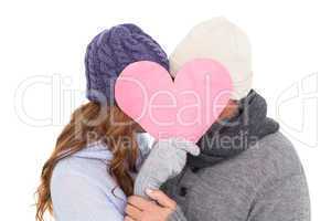 Couple in warm clothing holding heart