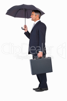 Businessman holding briefcase under umbrella