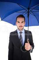 Cheerful businessman standing under umbrella