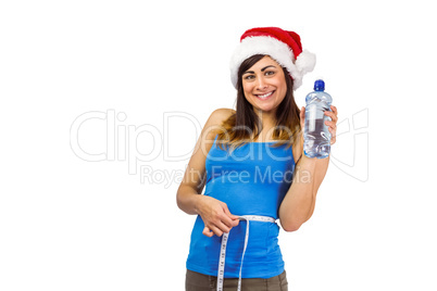 Festive fit brunette measuring her waist and holding bottle