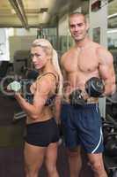 Couple exercising with dumbbells in gym