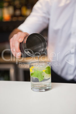 Bartender pouring cocktail into glass