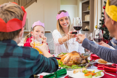 Family in party hat toasting at christmas dinner