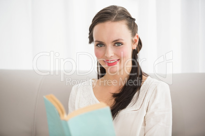 Pretty brunette reading book on couch