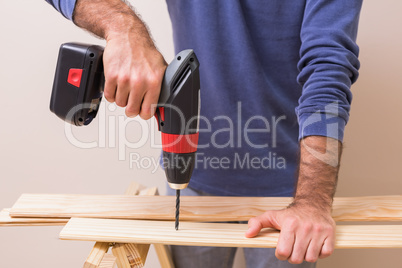 Casual man drilling hole in plank