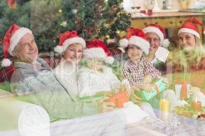 Three generation family opening christmas gifts on couch