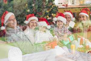Three generation family opening christmas gifts on couch