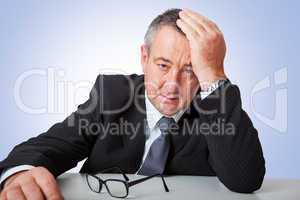 Businessman sitting at desk, holding his hand to his head
