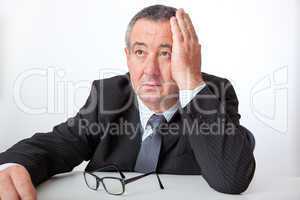 Businessman sitting at desk, holding his hand to his head