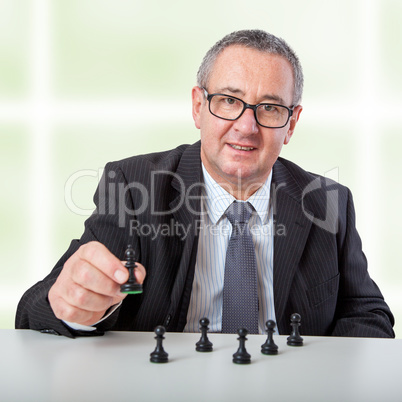 Man thinks strategically with chess pieces on the desk