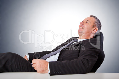 Happy man sitting at desk and leans back