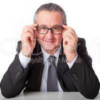 Man sitting at desk and has her hands on her glasses